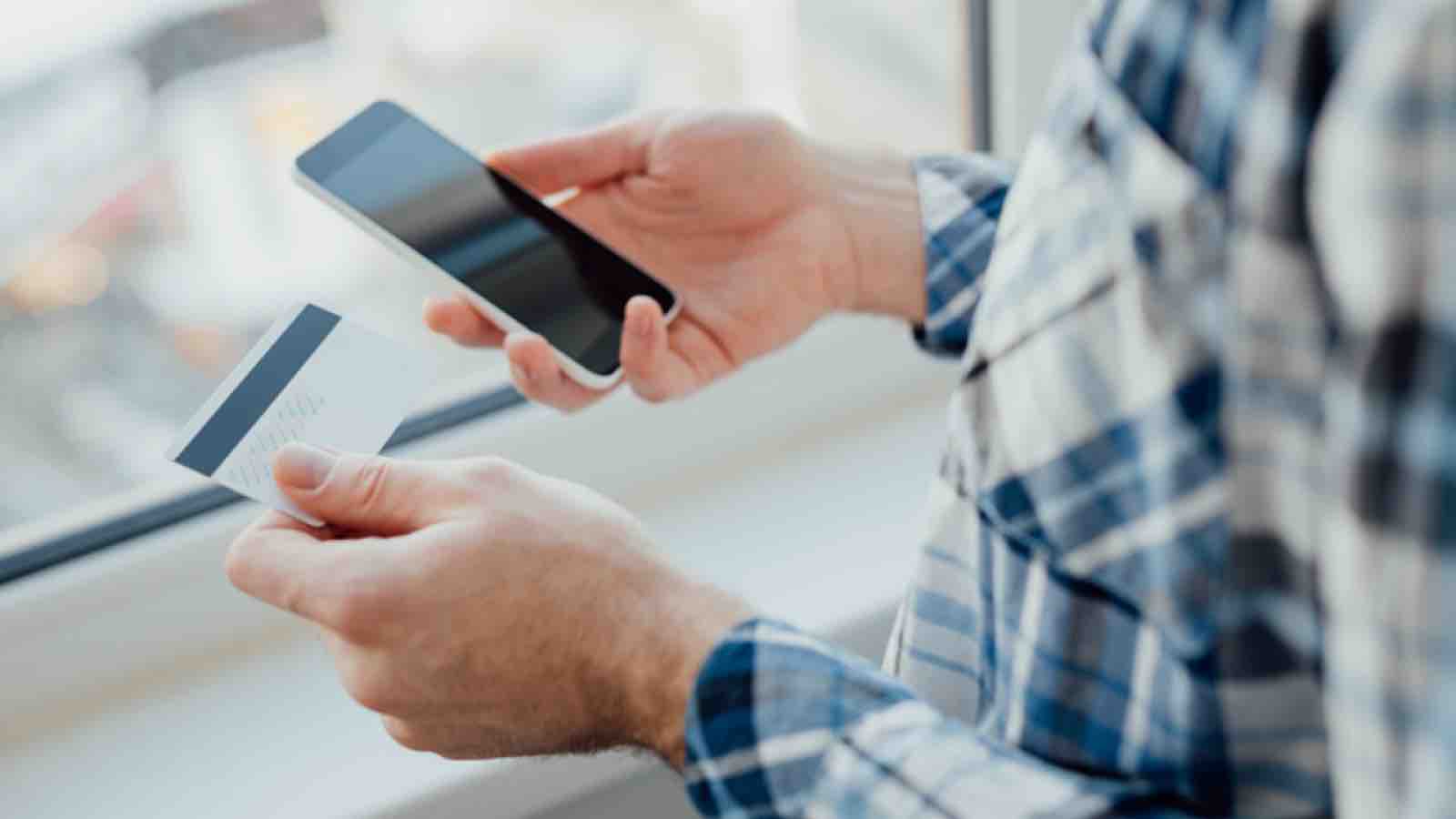 onlinesafetyshop Man holding a credit card and a smartphone